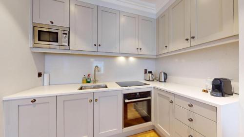 伦敦The Wimpole IX - 1 bed flat的白色的厨房配有白色的橱柜和微波炉