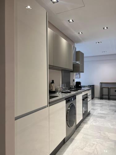 卡萨布兰卡Les Joyeux Luxury Suites & Appart的厨房配有白色橱柜、洗衣机和烘干机