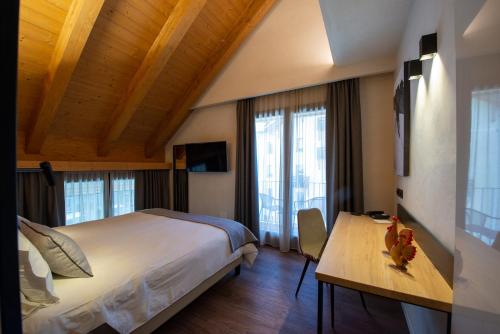 科涅Hotel Sant'Orso - Mountain Lodge & Spa的一间卧室配有一张大床、一张书桌和窗户。