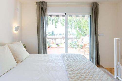 穆尔西亚La Casita del Malecón的卧室配有白色的床和滑动玻璃门