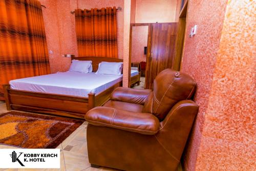 库马西Kobby Keach K. Hotel的一间卧室配有一张床和一张皮椅