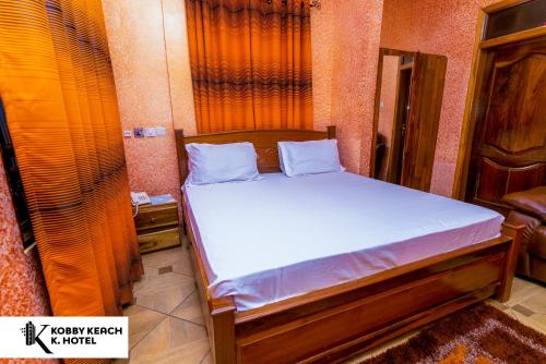 库马西Kobby Keach K. Hotel的小房间配有一张带白色床单的床