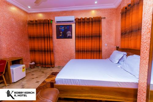 库马西Kobby Keach K. Hotel的一间卧室配有带橙色窗帘的大床