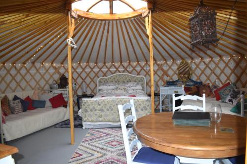 彭赞斯The Yurt in Cornish woods a Glamping experience的蒙古包内带桌子和沙发的房间
