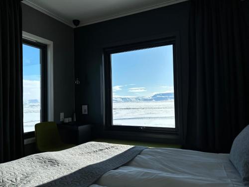 米湖拉夏酒店的一间卧室设有一张床和两个大窗户