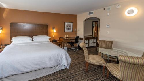温尼伯温尼伯国际机场福朋喜来登酒店的一间卧室配有一张床、一张桌子和一张桌子