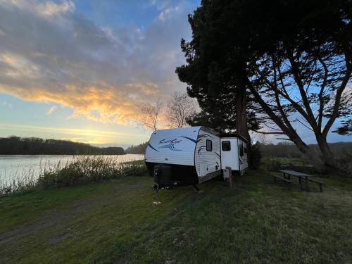 克拉马斯Surfside Glamping camper的停泊在湖边田野的拖车