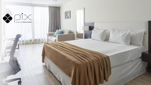 蒙得维的亚蒙得维的亚阿芙特酒店的酒店客房设有一张白色大床和椅子