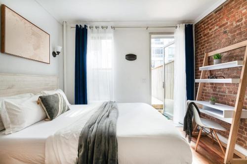 纽约24-4 New Private Terrace W D Apt Prime Gramercy的卧室配有白色的床和砖墙