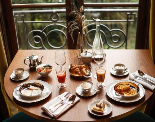 马夫列Hôtel Chateau de Maffliers - Demeures de Campagne的餐桌,带食物盘和酒杯