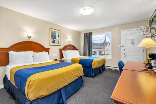 欧文桑德Nights Inn Owen Sound的酒店客房设有两张床和一张桌子。