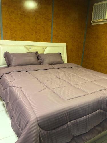 Sīdī Ḩamzahشاليه نزل أمنة的一张大床,配有紫色床单和枕头