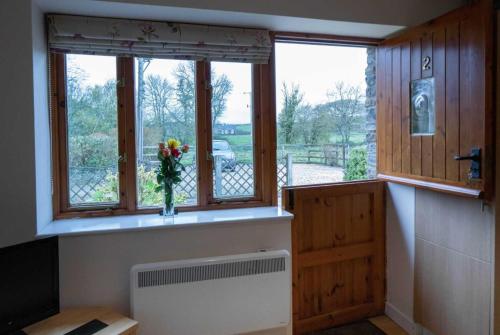 韦尔斯The Burcott Inn Cottages的一间设有花瓶的窗户的房间