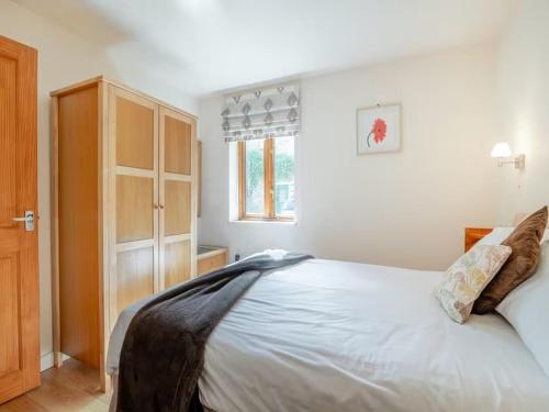 韦尔斯The Burcott Inn Cottages的卧室配有白色的床和木制橱柜。