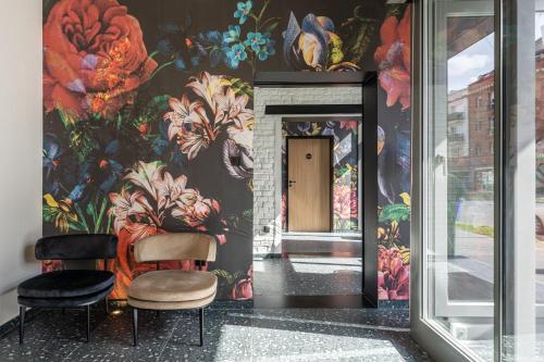 德布勒森URBAN HOTEL的走廊上设有两把椅子,墙上有鲜花