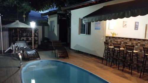 瓜拉派瑞Casa c/ Piscina e Área Gourmet, 5 min da praia.的一个带桌椅的游泳池和一个酒吧