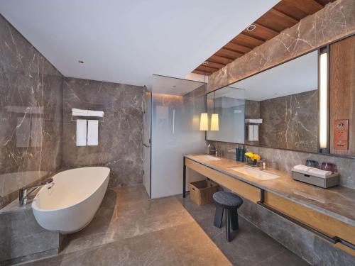 安图县长白山希尔顿逸林温泉酒店的一间带大浴缸和大镜子的浴室
