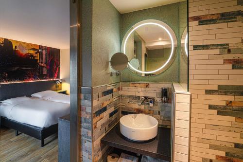 鹿特丹Maashotel Rotterdam Centre的浴室设有床、水槽和镜子