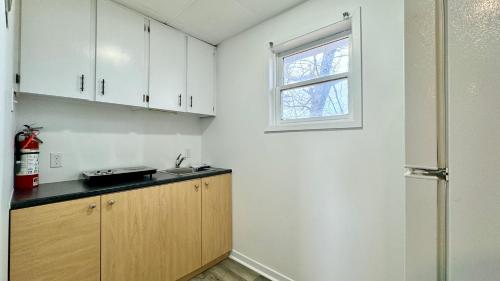萨默赛德SUMMERSIDE MOTEL &COTTAGES的厨房配有白色橱柜、水槽和窗户。