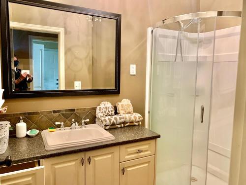 Pitt MeadowsLangley独立洗手间的一楼温馨客房的浴室配有盥洗盆和带镜子的淋浴