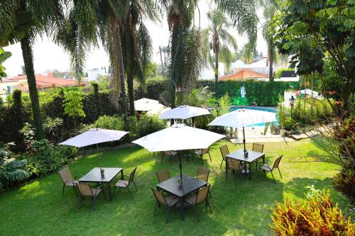 库埃纳瓦卡Hotel Grand Vista Cuernavaca的一组桌椅和遮阳伞