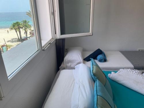 普拉亚登博萨Thee Ibiza Suites - Ushuaia Beach的客房设有两张床和一扇带海滩的窗户。