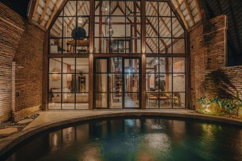 乌布Sanctuary Villas的一座带大窗户的建筑中的室内游泳池