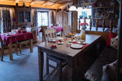 基姆湖畔贝尔瑙Gästehaus Sattlerhof的用餐室配有木桌、盘子和盘子