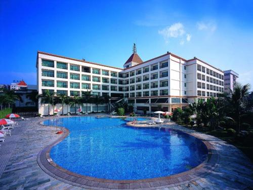 东莞Dongguan Metropolitan Yijing Hotel的大型酒店前方设有大型游泳池