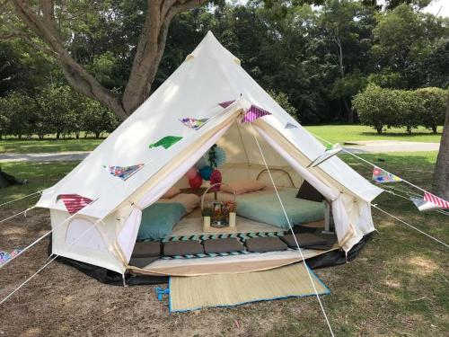 新加坡Glamping kaki singapore-Standard medium bell tent的田野上带床的白色帐篷
