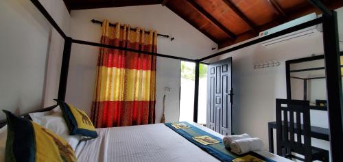 阿鲁甘湾Surf And Stay Arugam Bay的一间卧室配有华盖床和色彩缤纷的窗帘