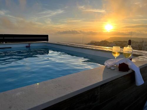 梅利哈Private Pool For Your Holiday In Mellieha的一个带酒杯和日落的游泳池