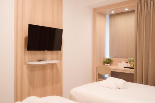武里南SNOW HOUSE Buriram的酒店客房,设有床铺和墙上的电视