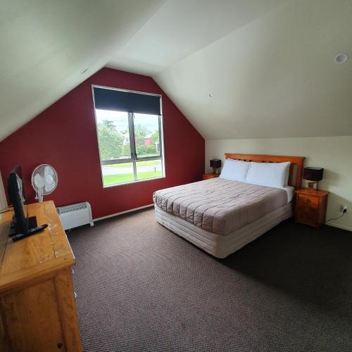 罗托鲁瓦Kuirau Chalet Villa 3-bedroom Twin Lake的一间卧室设有一张红色墙壁的大床