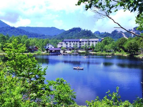 山之内町奇多伊科温泉酒店的湖上的小船,有建筑和树木