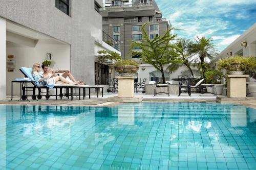 曼谷Cape House Langsuan Hotel的两人坐在游泳池旁的椅子上