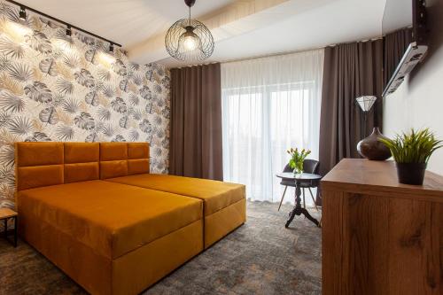 格里兹鲍Bursztynowa Przystań的一间卧室配有一张橙色大床和一张桌子