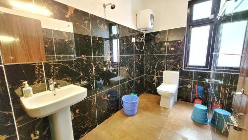 拉冲Wonder Hill Inn的黑色瓷砖浴室设有水槽和卫生间