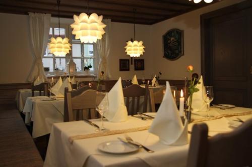 明德尔海姆Hotel und Gasthof Zur Laute的一间设有白色桌子和吊灯的用餐室