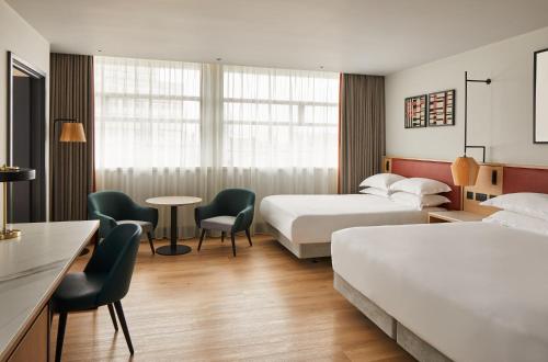 曼彻斯特Manchester Marriott Hotel Piccadilly的酒店客房带两张床和一张桌子以及椅子。