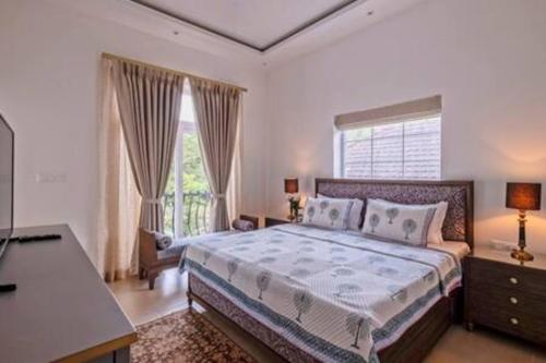 GoaAmanassa 2 Luxury 4BHK Villa with pool in Assagaon的一间卧室配有一张床、一张书桌和一个窗户。