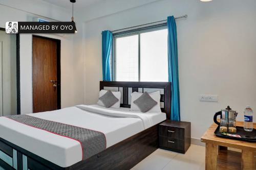 辛加瓦迪Townhouse Imperial Inn Hinjewadi的一间卧室配有一张带蓝色窗帘的床和一扇窗户