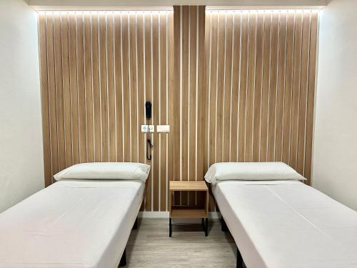 阿尔姆尼卡维多利亚中心酒店的医院客房的两张床位,设有木墙