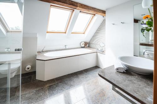 施韦比施哈尔利霸布鲁酒店的一间带水槽和浴缸的浴室以及窗户。