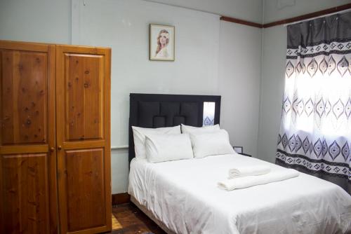 德班Gielex Guest House的一间卧室配有一张床和一个木制橱柜