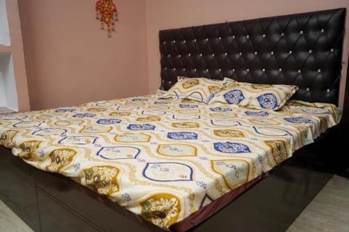 AyodhyaMalti Home stay 5 minute walking distance fromAyodhya DhamRailway Station的一张带黑色床头板和黄色及蓝色毯子的床