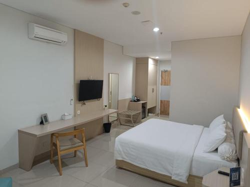 KedungbarukSkysuites Residence的一间卧室配有一张床、一张书桌和一台电视