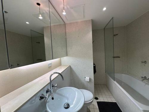 悉尼Cozy 2 Bedroom Apartment Darling Harbour的一间带水槽、浴缸和卫生间的浴室