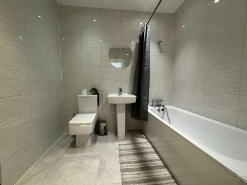 内兹岬附近沃尔顿Beautiful 1-Bed Apartment in Walton on the Naze的浴室配有卫生间、盥洗盆和浴缸。