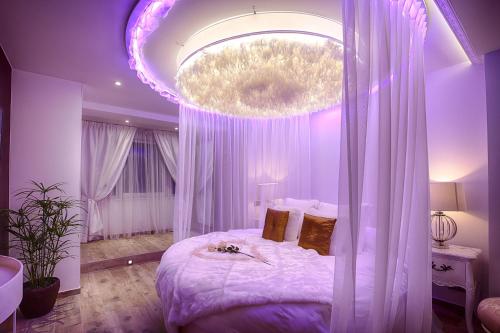 绍德方丹Le Clos des Thermes Suites de Luxe avec wellness privatif的一间卧室配有一张大床和紫色照明